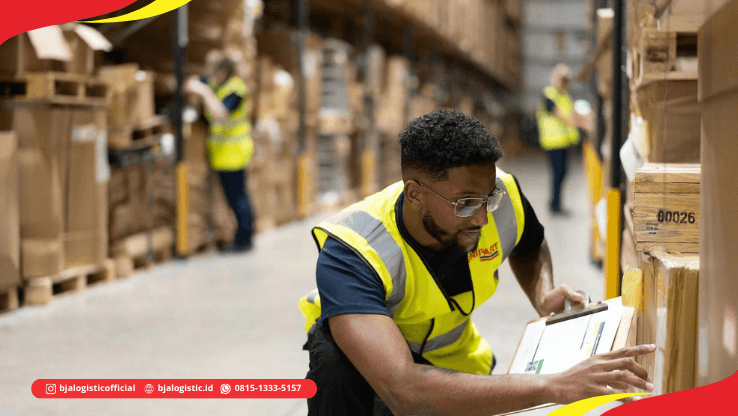 Pekerja gudang memeriksa dan mencatat informasi cargo menggunakan clipboard di area warehouse